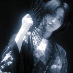 a woman in a kimono holding an umbrella over her head and looking off to the side