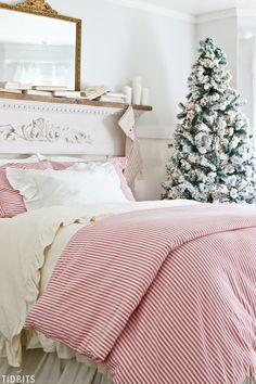 a christmas tree is in the corner of a bedroom with red and white bedding