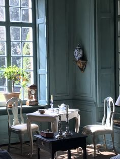 a living room filled with furniture next to a window covered in green shuttered windows