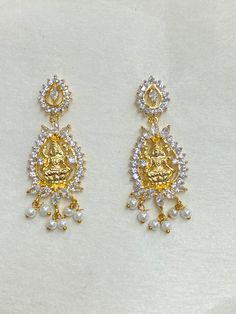 Welcome to Ray Fineornates Jewellery, where Divine Opulence meets exquisite craftsmanship! Our Gold Plated Temple Earring Set featuring the iconic South Indian Lakshmi design is a true reflection of timeless beauty and tradition. These earrings are meticulously crafted with 22k yellow gold plating, capturing the essence of authentic Temple jewellery. The intricate Lakshmi Ji design showcases the goddess of wealth and prosperity, symbolizing divine blessings and grace. At Ray Fineornates Jeweller Gold Earrings For Puja, Elegant Earrings For Diwali Puja, Dangle Latkans Earrings For Puja, Elegant Earrings For Puja And Diwali, Elegant Latkans Earrings For Puja, Latkan Dangle Earrings For Puja, Gold Jewelry With Matching Earrings For Navratri, Elegant Danglers For Puja, Temple Jewelry Style Bridal Earrings