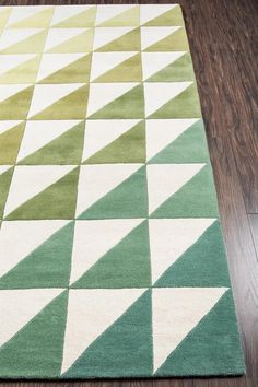 a green and white area rug on a wooden floor with wood floors in the background