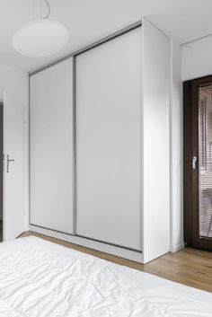 an empty bedroom with white walls and wood flooring is pictured in this image, there are sliding doors on both sides of the bed