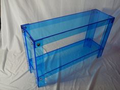 a blue glass shelf sitting on top of a white sheeted floor next to a wall