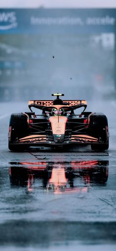 a race car driving down a wet track with its lights reflecting in the wet ground