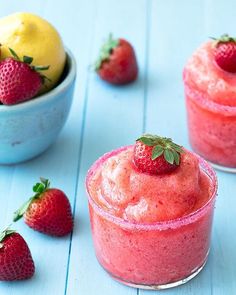 two small cups with strawberries and lemons next to them on a blue table