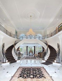 a large foyer with stairs and chandelier in the center, surrounded by marble flooring