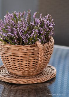 a wicker basket filled with purple flowers on top of a table