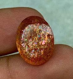 a close up of a person's hand holding a small piece of gold glitter