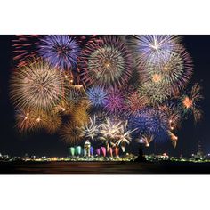 fireworks are lit up in the night sky over a body of water and city buildings