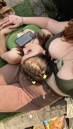 two women laying on the ground with their cell phones