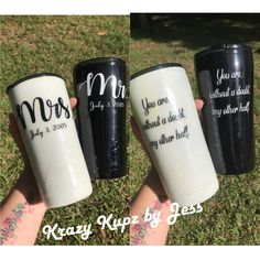 three coffee mugs with names on them sitting in the grass, one is black and one is white