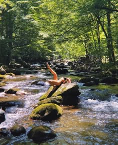 a person laying on top of a rock in a river