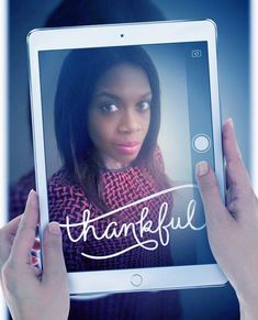 a woman holding up a tablet with the words thank you on it in front of her face