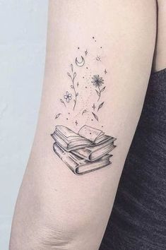 a woman's arm with a tattoo on it that has an open book and stars flying