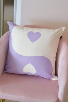 a pink chair with a purple and white pillow on it