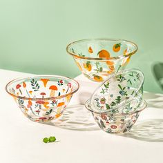 three glass bowls sitting on top of a table next to each other with oranges painted on them