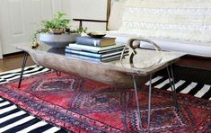 a coffee table with books on it in front of a couch and potted plant