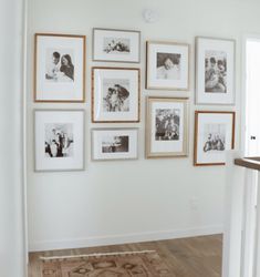 a wall with many pictures on it and a rug in front of the door way