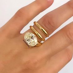 a woman's hand with a gold ring and an oval diamond