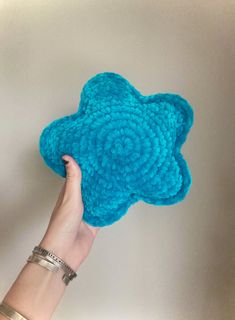 a hand holding up a blue crocheted flower