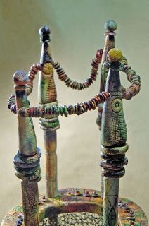 an artistic sculpture made out of metal pipes and beads on a stand with two heads