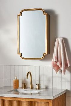 a bathroom with a sink, mirror and towel hanging on the wall next to it