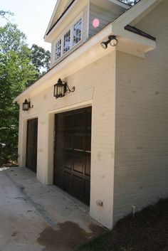 two garages are shown in front of a white brick building with black doors and windows