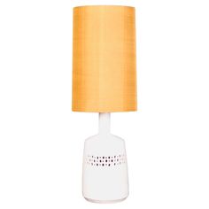 a white table lamp with a yellow shade on it's base and a light bulb in the middle