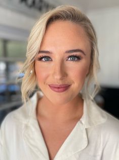 a woman with blonde hair and blue eyes wearing a white shirt looking at the camera