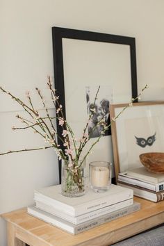 a vase filled with flowers sitting on top of a table next to books and a candle