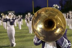 a marching band is playing on the field with their brass instruments in front of them