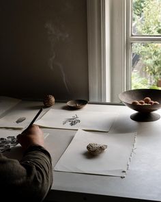 a person sitting at a table with some papers and a bowl on top of it