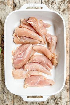 raw chicken in a white dish on a wooden table