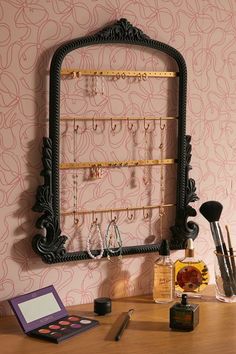 a desk with a mirror and jewelry rack on it's wall, along with other items