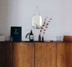 a wooden cabinet sitting next to a mirror and vase on top of it's side