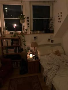 a small bedroom with a bed, window and bookshelf in the corner at night