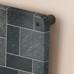 the corner of a wall with a black tile pattern on it and a metal handle