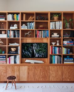 a living room with bookshelves and a television on the wall in front of it