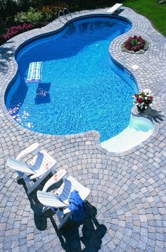 a swimming pool surrounded by a patio and lawn chairs