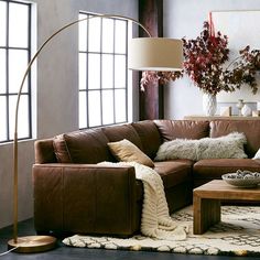 a living room with a brown leather couch and white rugs on the floor next to a large window