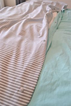 an unmade bed with blue and white sheets