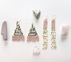 beaded earrings and other accessories laid out on a white surface next to a rock