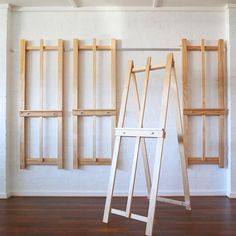 an easel leaning against the wall in front of three wooden frames on a hard wood floor