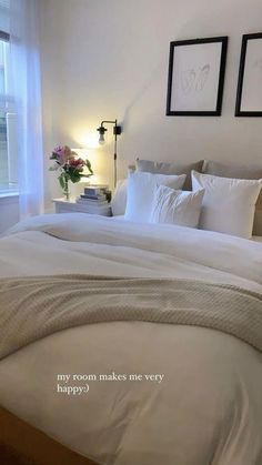 a bed with white linens and pillows in a bedroom next to two pictures on the wall