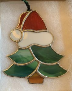 a stained glass christmas tree ornament hanging from a string on a white background