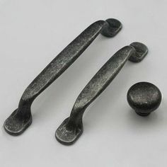 three metal handles and two knobs on a white surface