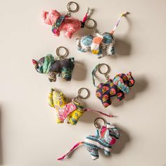 several small elephant keychains are arranged on a white surface, one has a pink ribbon and the other is blue