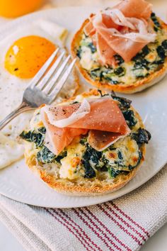 an egg, ham and spinach breakfast sandwich on a white plate with a fork