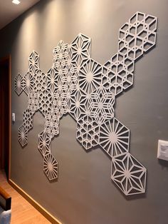 the wall is decorated with intricate paper cut art pieces, including geometric shapes and lines