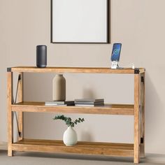 a wooden shelf with a vase and cell phone on it in front of a wall